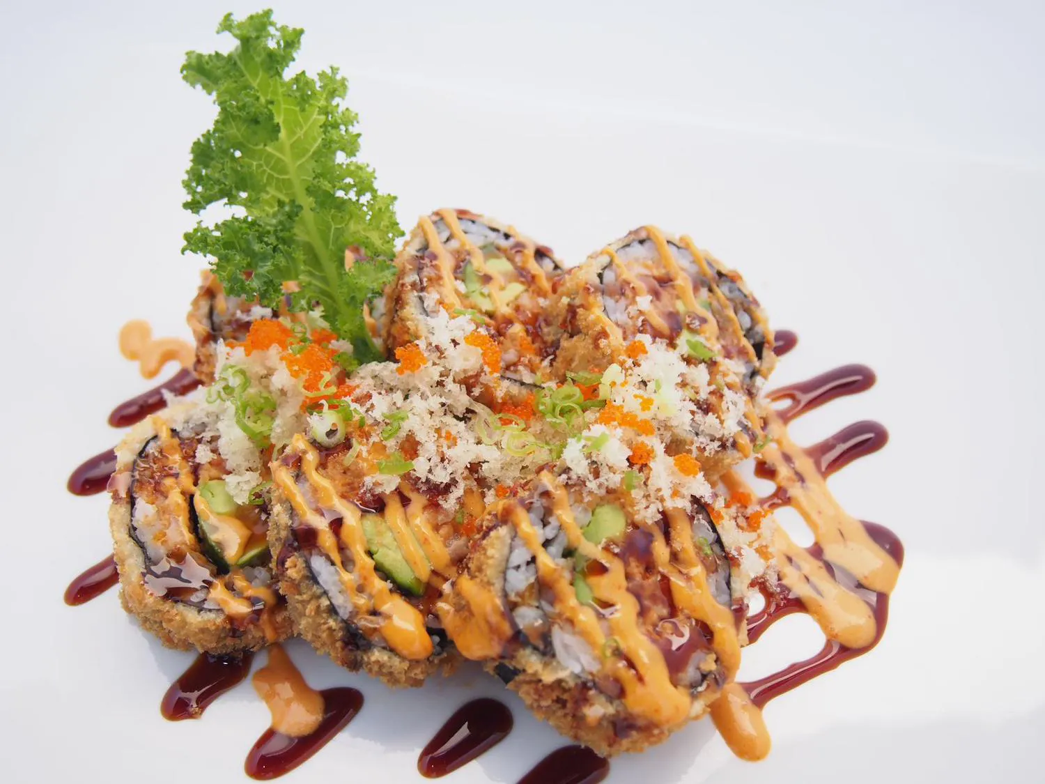 Crispy fried sushi roll with spicy sauce, tempura flakes and orange tobiko