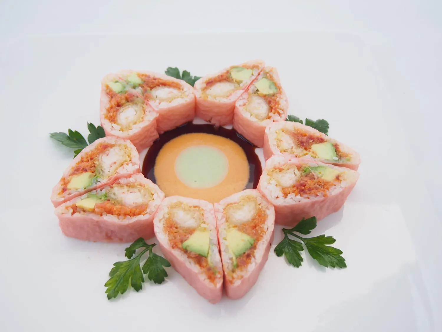 Pink wrapped sushi roll arranged in flower shape with two dipping sauces